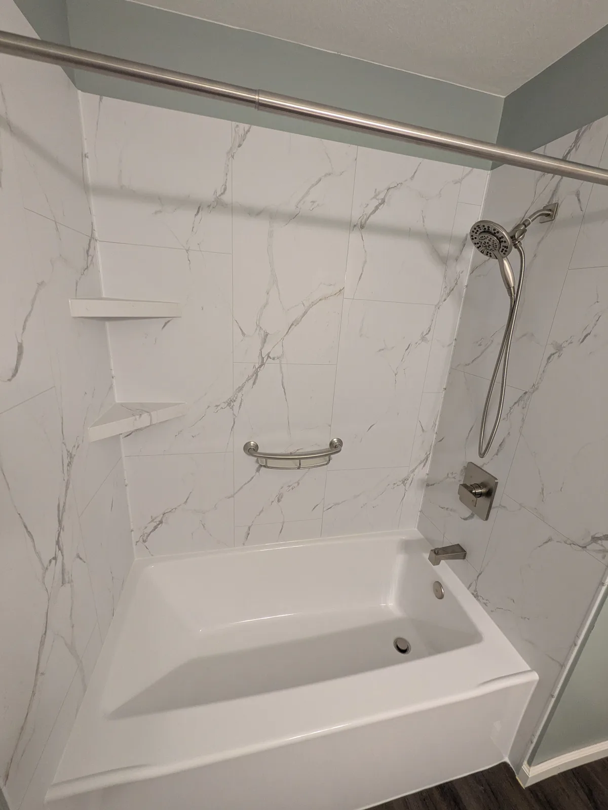 New tub surround in marble-look panels with a handheld shower