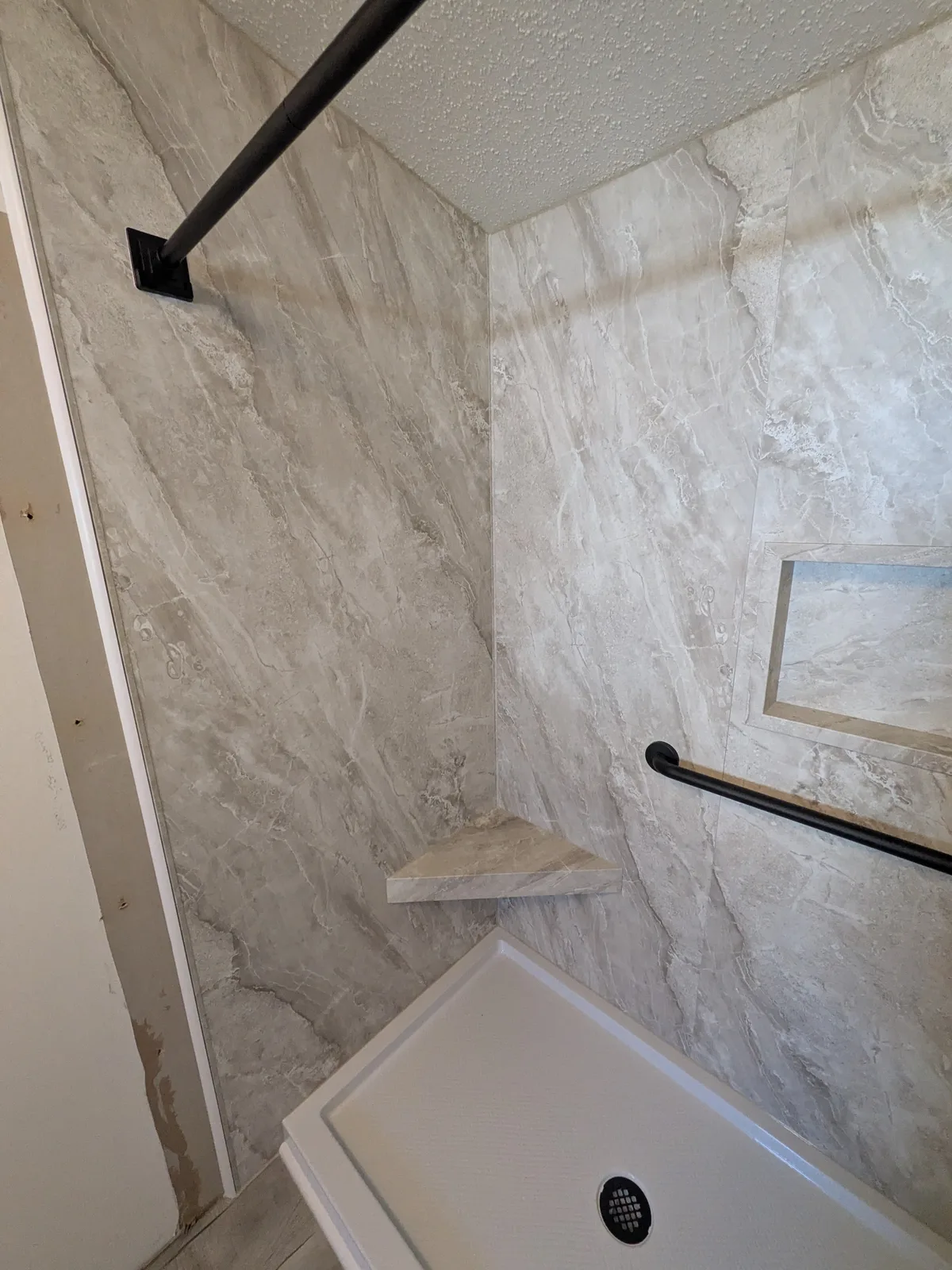 Completed marble-look shower with black sliding glass
